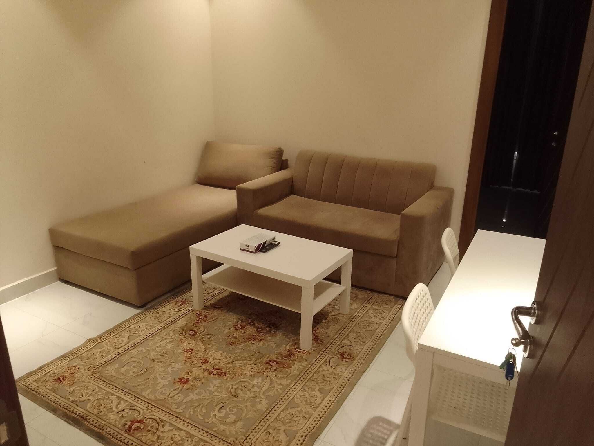 Un pequeño espacio de sala con un sofá, una mesita de centro y una alfombra estampada.