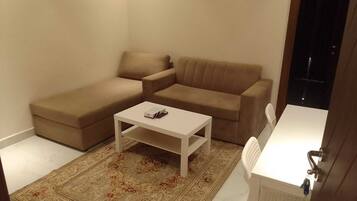 Un pequeño espacio de sala con un sofá, una mesita de centro y una alfombra estampada.