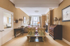 A hallway with a sofa, a table with a vase, a dresser, and a mirror. - Fulham Family Home Near Thames Path (London)