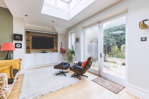 Un salon moderne doté d’un téléviseur, de sièges et offrant une vue sur l’extérieur.