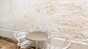 A metal table and two chairs against a white brick wall. - Marylebone Boutique Retreat (London)