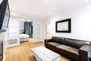 Ein modernes Wohnzimmer mit einem braunen Ledersofa, einem weißen Couchtisch und einem an der Wand montierten Fernseher.