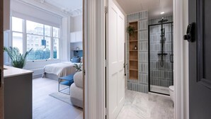 Een moderne slaapkamer met een groot raam, een nachtkastje, een stoel en een bed.