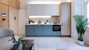 Een moderne keuken met lichte houten kastjes, een inbouwoven en een centraal eiland.