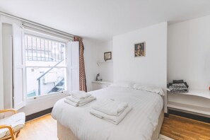 A bedroom with a bed, a window, a chair, a bedside table, and a shelf. - Bright Islington One Bedroom Retreat (London)