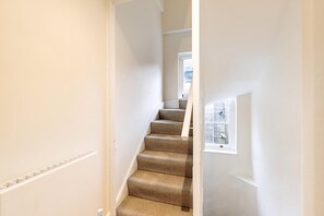 Eine schmale Treppe mit Teppichstufen, die zu einer Zwischenebene führt.