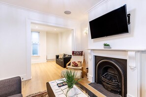 Ein Wohnzimmer mit Kamin, Flachbildfernseher, Sofa und Sessel.