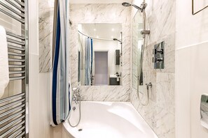 Une salle de bain moderne avec un mur en marbre, une baignoire, une douche et un porte-serviettes.