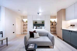 Ein modernes Schlafzimmer mit einem Bett, einer Couch, einem kleinen Tisch und integrierten Schränken.