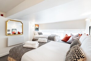 Ein Hotelzimmer mit einem großen Bett, einer Sitzecke, einem Vorhangfenster, einem wandmontierten Spiegel und einem gerahmten Bild.