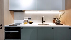 Eine moderne Küche mit eingebautem Geschirrspüler, einer Spüle und einer Arbeitsplatte, auf der sich ein Pastaglas, eine Obstschale und eine dekorative Vase befinden.
