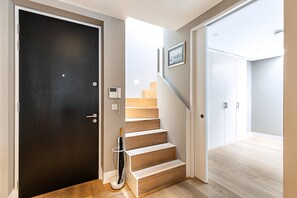 Ein modernes Interieur mit einer dunklen Tür, Holzwänden, einem weißen, an der Wand befestigten Telefon und einem gerahmten Bild.