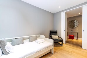 Ein modernes Zimmer mit einem weißen Sofa, einem schwarzen Sessel und einem roten Hocker.