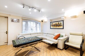 Ein modernes Wohnzimmer mit einer Eckcouch, einem Klapptisch und einem Relaxsessel.