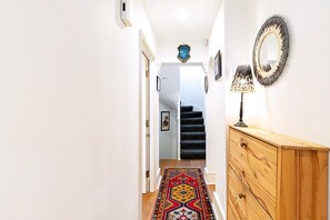 Ein Flur mit einem gemusterten Teppich, einer hölzernen Kommode und einem Spiegel an der Wand.