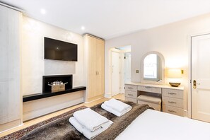 Ein modernes Schlafzimmer mit Bett, Schminktisch, Kleiderschrank, Flachbildfernseher und Spiegel.