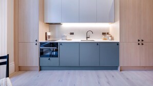 Una cucina moderna con mobili in legno chiaro, forno integrato e lavello in acciaio inossidabile.