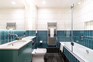 Ein modernes Badezimmer mit einem großen Waschbecken, einer Toilette und einer Badewanne.