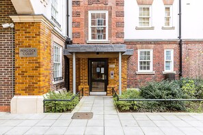 A brick building with a sign reading 'PEACOCK COURT' and a door marked '1-24'. - Modern and Elegant Apartment in West Kensington (London)