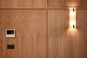 Eine Holzwand mit einer integrierten Leuchte und einem kleinen Bedienfeld.