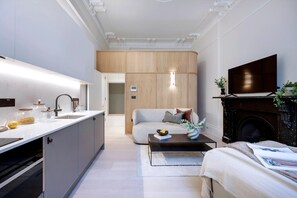 Eine moderne Küche mit Einbauofen, ein Essbereich mit Sofa und Couchtisch sowie ein Wohnzimmer mit Kamin und Fernseher.