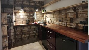 A kitchen with exposed brick walls, wooden countertops, a sink, and a dishwasher. - Architect Designed Studio Borough (London)