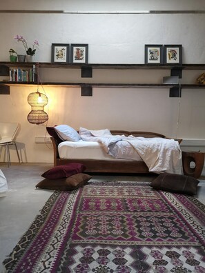 A bedroom with a bed, a patterned rug, a hanging light fixture, and framed artwork on the wall. - Architect Designed Studio Borough (London)