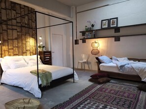 A bedroom with a four-poster bed, a chair, a bookshelf, and a patterned rug. - Architect Designed Studio Borough (London)