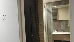 A modern bathroom with a dark door, tiled walls, a glass shower enclosure, and a sink with a mirror. - Architect Designed Studio Borough (London)