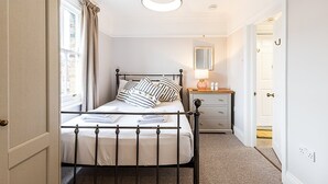 A neatly arranged bedroom with a bed, bedside table, and a mirror. - Stylish Marylebone City Apartment (London)