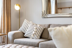 A living room with a sofa, striped pillows, a floor lamp, and a mirror. - Stylish Marylebone City Apartment (London)