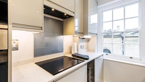 A modern kitchen with a built-in stove, a window with a view of a bridge, and a towel rack. - Stylish Marylebone City Apartment (London)