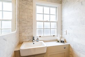 A bathroom with a white sink, a window, and a mirror. - Stylish Marylebone City Apartment (London)