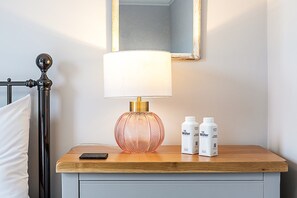 A bedside table with a lamp, two water bottles, and a smartphone. - Stylish Marylebone City Apartment (London)