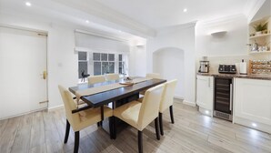 A modern kitchen with white cabinets, a built-in oven, and a countertop with various appliances. - Refined Pimlico Townhouse (London)