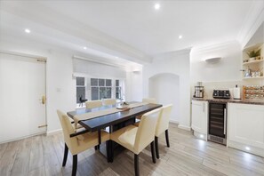 A modern kitchen with white cabinets, a built-in oven, and a countertop with various appliances. - Refined Pimlico Townhouse (London)