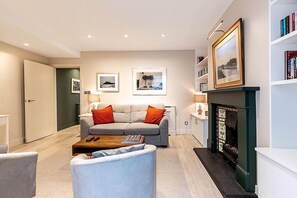 Ein modernes Wohnzimmer mit einer Couch, einem Couchtisch, einem Kamin und gerahmten Bildern an der Wand.