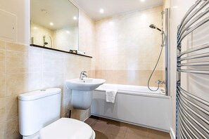 A modern bathroom with a toilet, sink, and bathtub. - Bow Retreat Near Victoria Park (London)