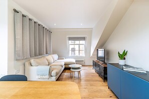 Ein modernes Wohnzimmer mit Sofa, Couchtisch und Fernseher.