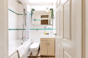 Ein Badezimmer mit Badewanne, Toilette, Waschbecken und Spiegel.