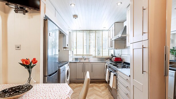 A compact kitchen with a washing machine, a stove, and a sink. - London Home With Garden Near Richmond Park (London)
