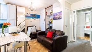 A compact living space with a dining area, a sofa, a coffee table, and a kitchen area. - London Home With Garden Near Richmond Park (London)