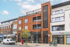 A multi-story building with a mix of brick and modern architecture, storefronts, and a parked bicycle. - Stylish Wimbledon Flat With Balcony (London)