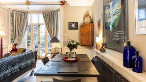 A dining area with a table, chairs, a vase with flowers, a clock, and a framed picture on the wall. - Elegant Highgate Garden Retreat (London)