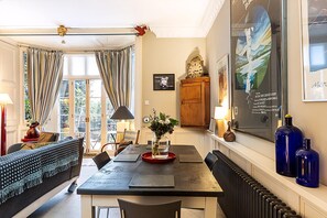 Ein Essbereich mit Tisch, Stühlen, einer Blumenvase, einer Uhr und einem gerahmten Bild an der Wand.
