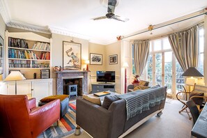 Ein Wohnzimmer mit Kamin, Bücherregalen, einem Fernseher und einem Sofa.