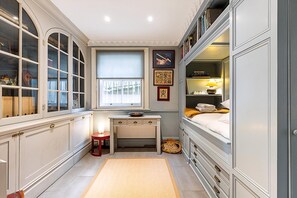 Ein schmales Zimmer mit Fenster, Schreibtisch und Bett.
