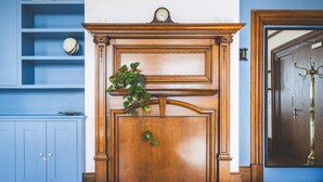 Une cheminée en bois avec une horloge, un meuble bleu et une porte dotée d’une poignée en laiton.