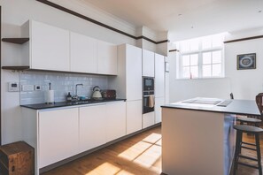 Eine moderne Küche mit weißen Schränken, einer schwarzen Arbeitsplatte und einem Fenster, das für natürliches Licht sorgt.