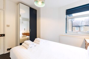 Ein Hotelzimmer mit Bett, Spiegel, Fenster und Heizkörper.